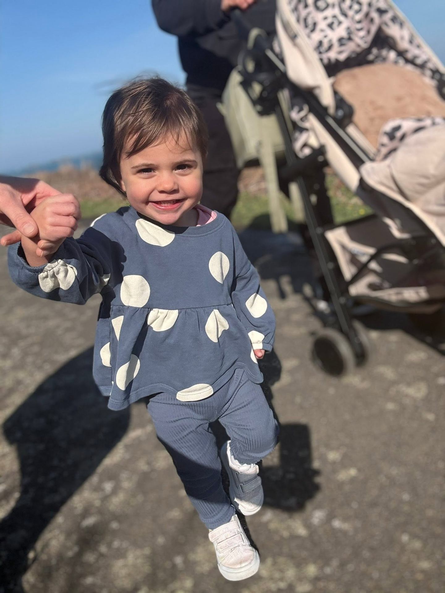 Toddler in polka dots holding hands on a walk